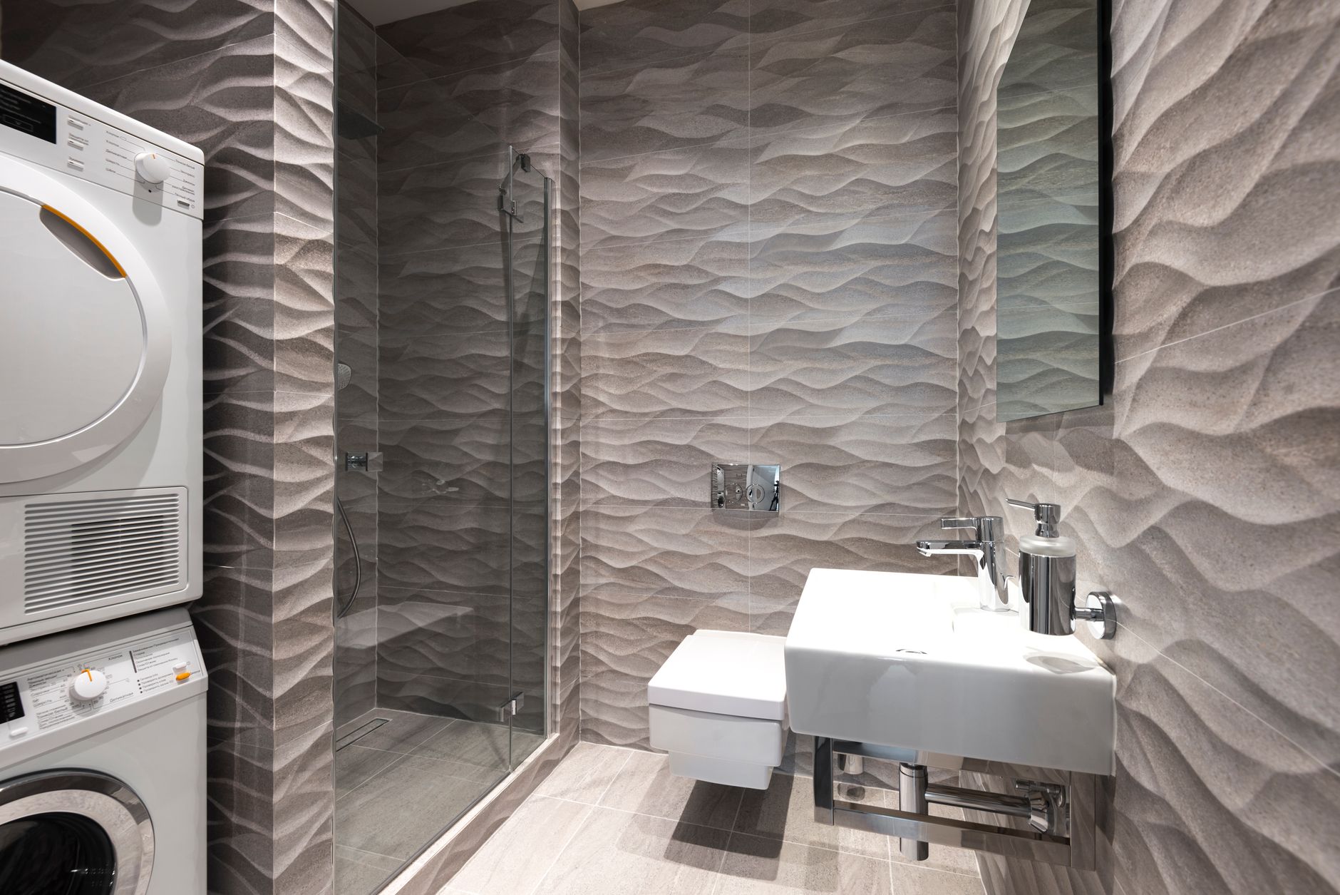 A stylish and contemporary bathroom featuring a shower, sink, and in-built washer and dryer.