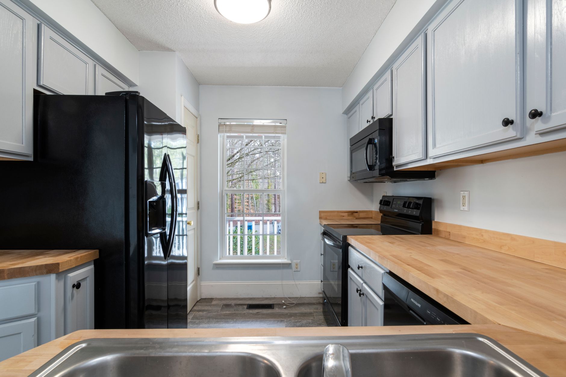 Bright and spacious kitchen featuring modern design with wooden countertops and stainless steel appliances.